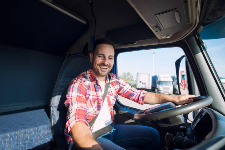 Motorista de caminhão feliz dentro do veículo e vestindo uma camisa xadrez