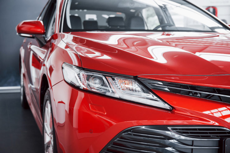 foto de um carro vermelho visto de frente, com foco no farol dianteiro